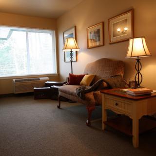 A cozy living room with a sofa, table lamps, and artwork on the walls.