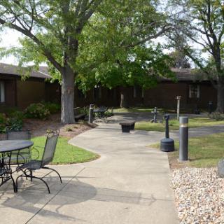 A serene garden pathway surrounded by greenery and seating areas.