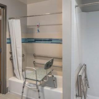 An accessible bathroom with a shower chair and grab bars.