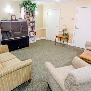 A cozy living room with comfortable seating, a large television, and a bookshelf.