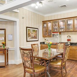 A cozy dining area with wooden furniture and a well-equipped kitchen in the background.