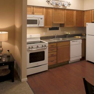 A modern kitchen with wooden cabinets and various appliances including a stove, microwave, fridge, and dishwasher.