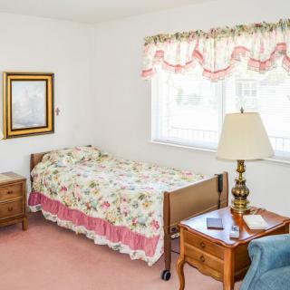A cozy bedroom with floral bedding and a bright window.