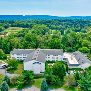 Aerial view of a large building nestled in lush greenery and rolling hills.