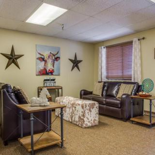 A cozy living room with leather couches, decorative stars, and a cow painting on the wall.