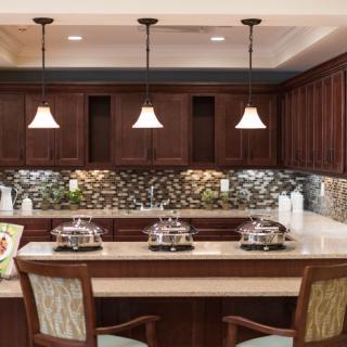 A beautifully designed kitchen featuring a bar counter with pendant lighting and rich wood cabinetry.