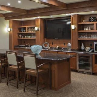 A stylish home bar setup with wooden cabinetry, a sleek countertop, and modern amenities.