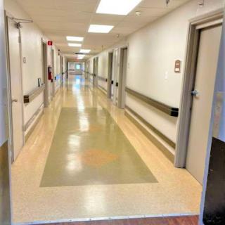 A long, well-lit hallway in a hospital featuring clean floors and multiple doors.