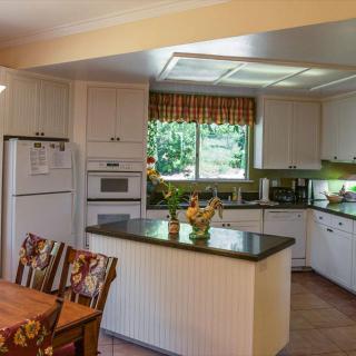 A modern kitchen with an island countertop, dining area, and large window letting in natural light.