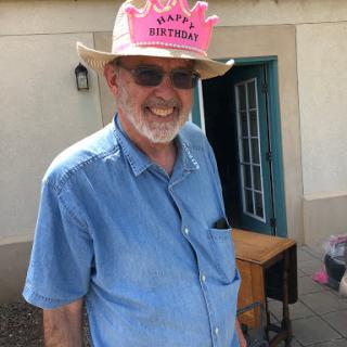 A cheerful man celebrating his birthday, wearing a festive pink hat.