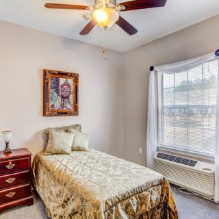 A cozy bedroom with a single bed, ceiling fan, and large window.