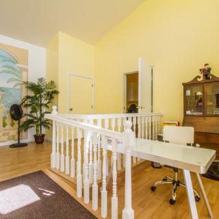 A bright and cozy home office space with a desk, chair, and bookshelf, complemented by yellow walls and wood flooring.