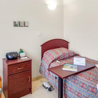 A cozy bedroom featuring a single bed with patterned bedding and a nightstand beside it.