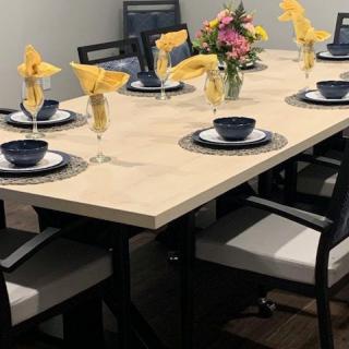 A dining table elegantly set with yellow napkins, blue tableware, and a floral centerpiece.