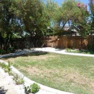 A well-maintained backyard with a lawn, trees, and a wooden fence.