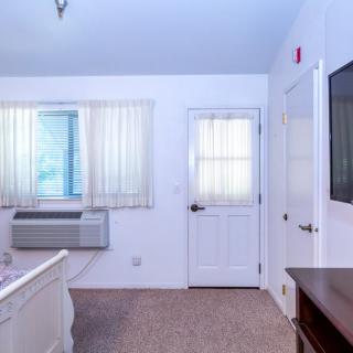 A cozy bedroom with an air conditioner, TV, and soft lighting.