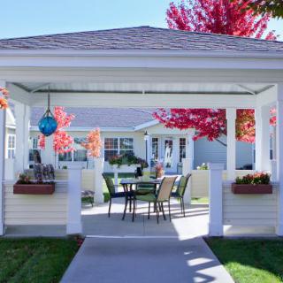 A cozy outdoor gazebo with seating, surrounded by autumn foliage.