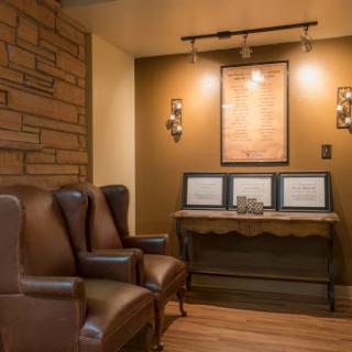 A cozy interior space featuring comfortable leather chairs, artistic wall decor, and warm lighting.