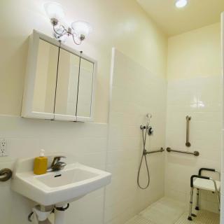 An accessible bathroom with a walk-in shower, grab bars, and a shower chair.