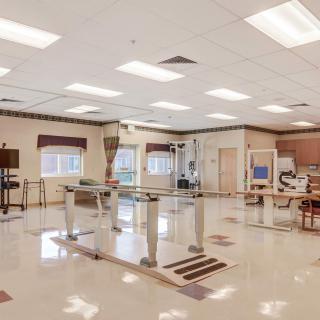 A spacious physical therapy room with exercise equipment and rehabilitation tools.