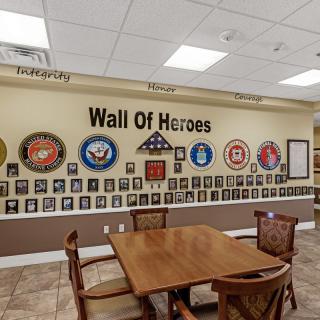 A room with a 'Wall of Heroes' displaying military insignia and portraits honoring veterans.