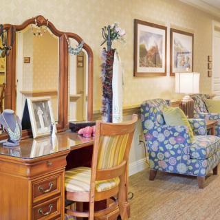A cozy living room interior with a wooden vanity, upholstered chairs, and decorative artwork.