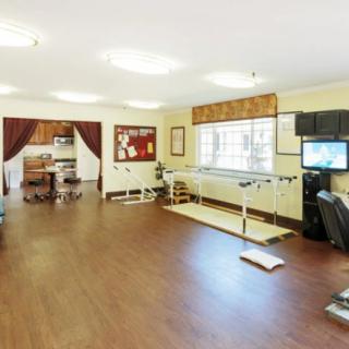 A spacious rehabilitation room with exercise equipment and parallel bars for physical therapy.