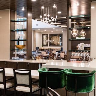 A modern and luxurious kitchen interior featuring elegant lighting, comfortable bar stools, and a sleek countertop.