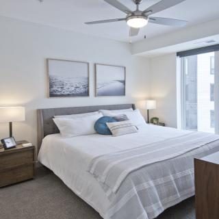 A modern, minimalist bedroom with a large bed, elegant decor, and ample natural lighting.
