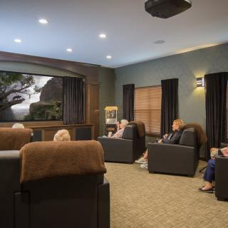 A group of people enjoying a movie in a cozy home theater with comfortable seating.