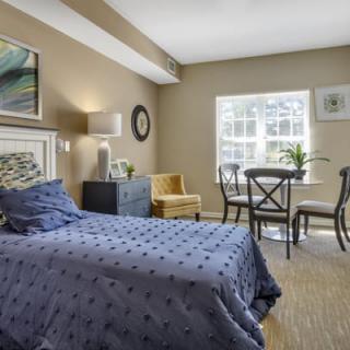 Cozy bedroom with a bed, side table, and seating area in natural light.