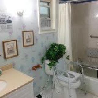 A small bathroom with a toilet, sink, and bathtub featuring wall art and a potted plant.