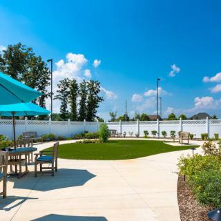 A sunny outdoor patio with furniture and a garden area.
