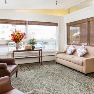 A cozy and well-lit living room featuring a comfortable sofa, armchairs, and a vibrant floral arrangement.