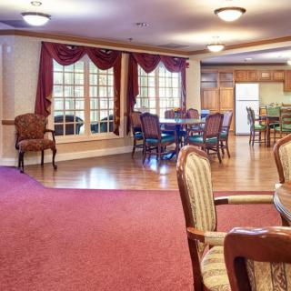 A spacious dining and kitchen area featuring elegant furniture, hardwood floors, and warm lighting.
