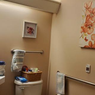 A cozy bathroom featuring warm tones, decorative artwork, and neatly organized essentials.