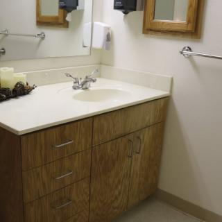 A bathroom with a wooden cabinet, sink, and mirror.