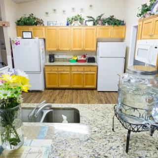 A cozy kitchen featuring wooden cabinets, modern appliances, and a decorative touch with fresh flowers.