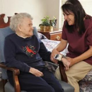 A caregiver provides assistance to an elderly woman in a comfortable home setting.
