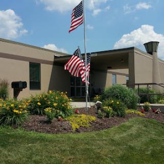 A well-maintained building with American flags and colorful flowers in the foreground.