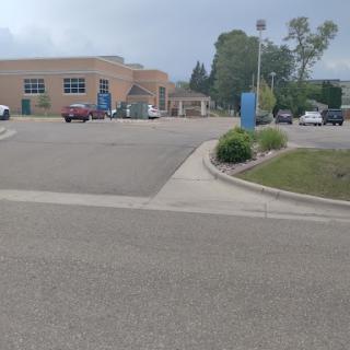 A view of a parking lot in front of a building on a cloudy day.