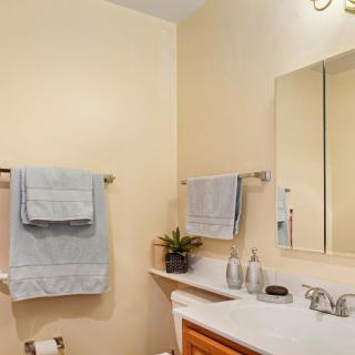 A minimalist bathroom featuring soft towels, a large mirror, and a tidy sink area.