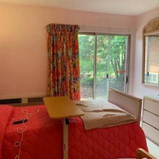 A cozy bedroom with red bedding and a view of the garden through a sliding glass door.