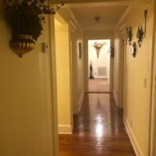 A warmly lit hallway with wooden floors and wall decorations.