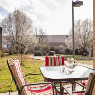 A sunny patio with a table and chairs overlooking a garden.