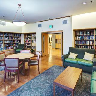 A cozy library reading room with comfortable seating and bookshelves lining the walls.