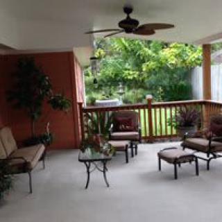 A cozy covered patio with comfortable seating and a view of the garden.