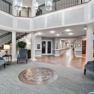 A spacious and elegant lobby with a chandelier, seating area, and carpeted floor.