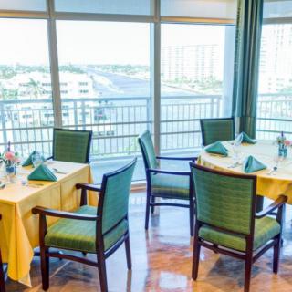 A well-set dining area with tables and chairs overlooking a scenic view through large windows.