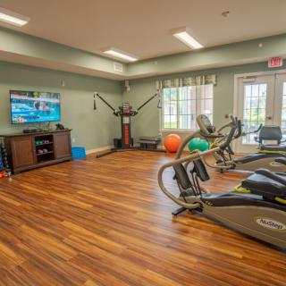 A well-equipped gym with treadmills, fitness equipment, and a television in a bright room.